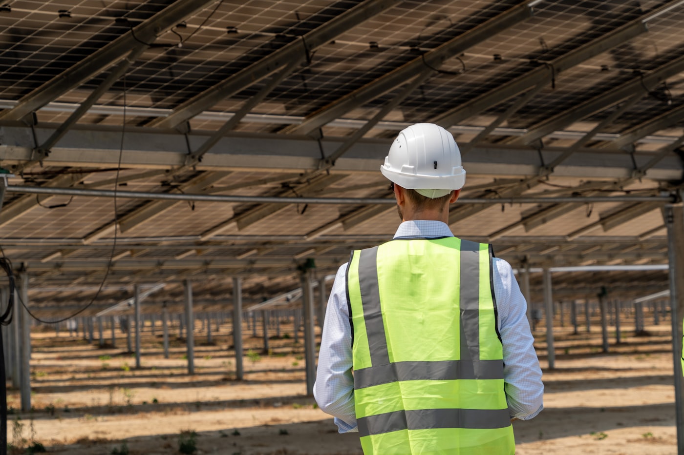 Technicien en gilet de sécurité sous une grande installation photovoltaïque