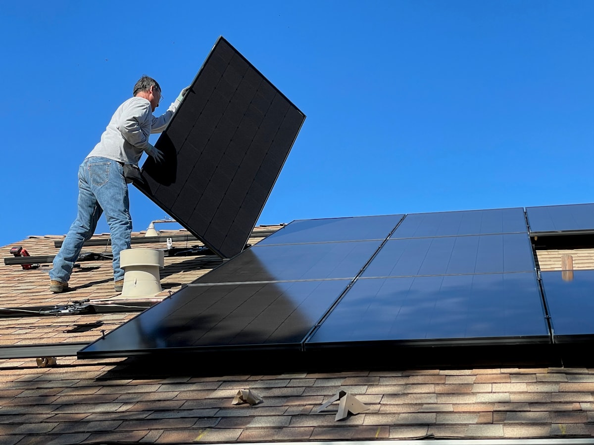 Ouvrier portant un panneau photovoltaïque sur une toiture