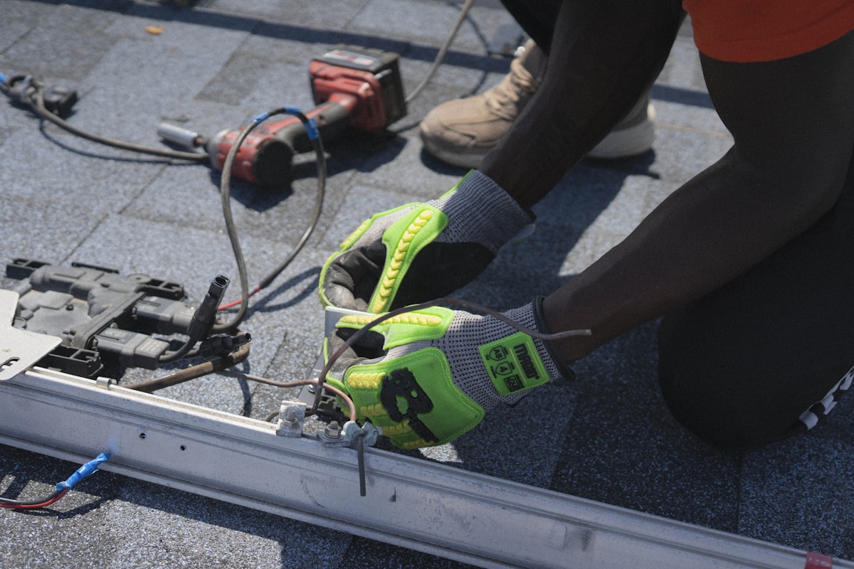 Mains d'un technicien installant un composant électrique en toiture